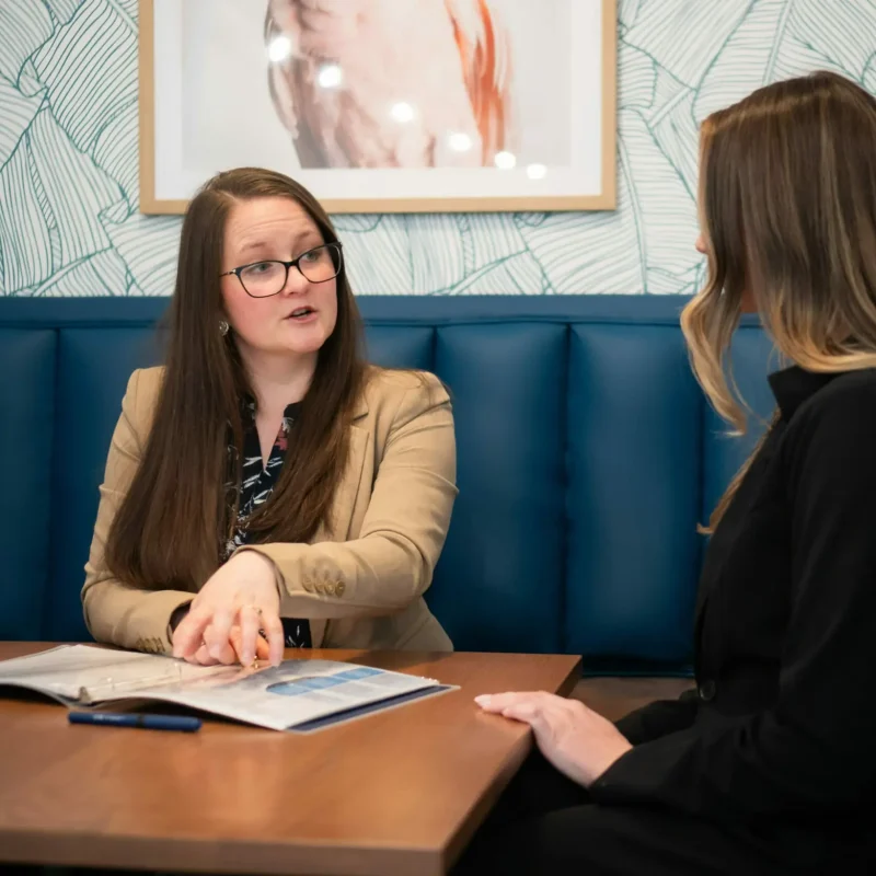 A consultant explains a report with a client at a table.